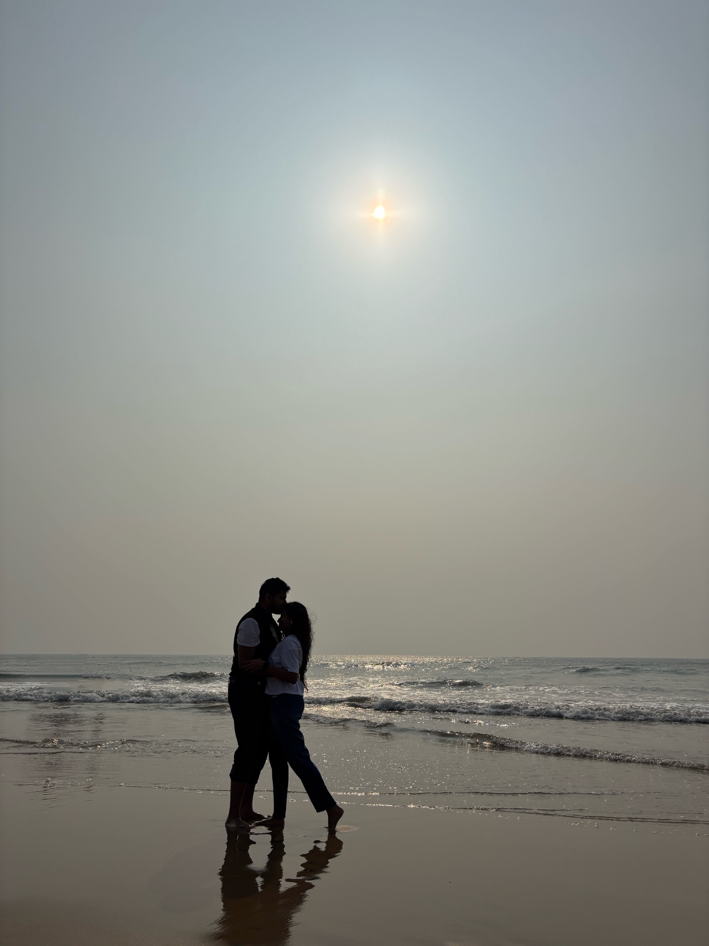 Couple silhouetted against the sea at dusk
