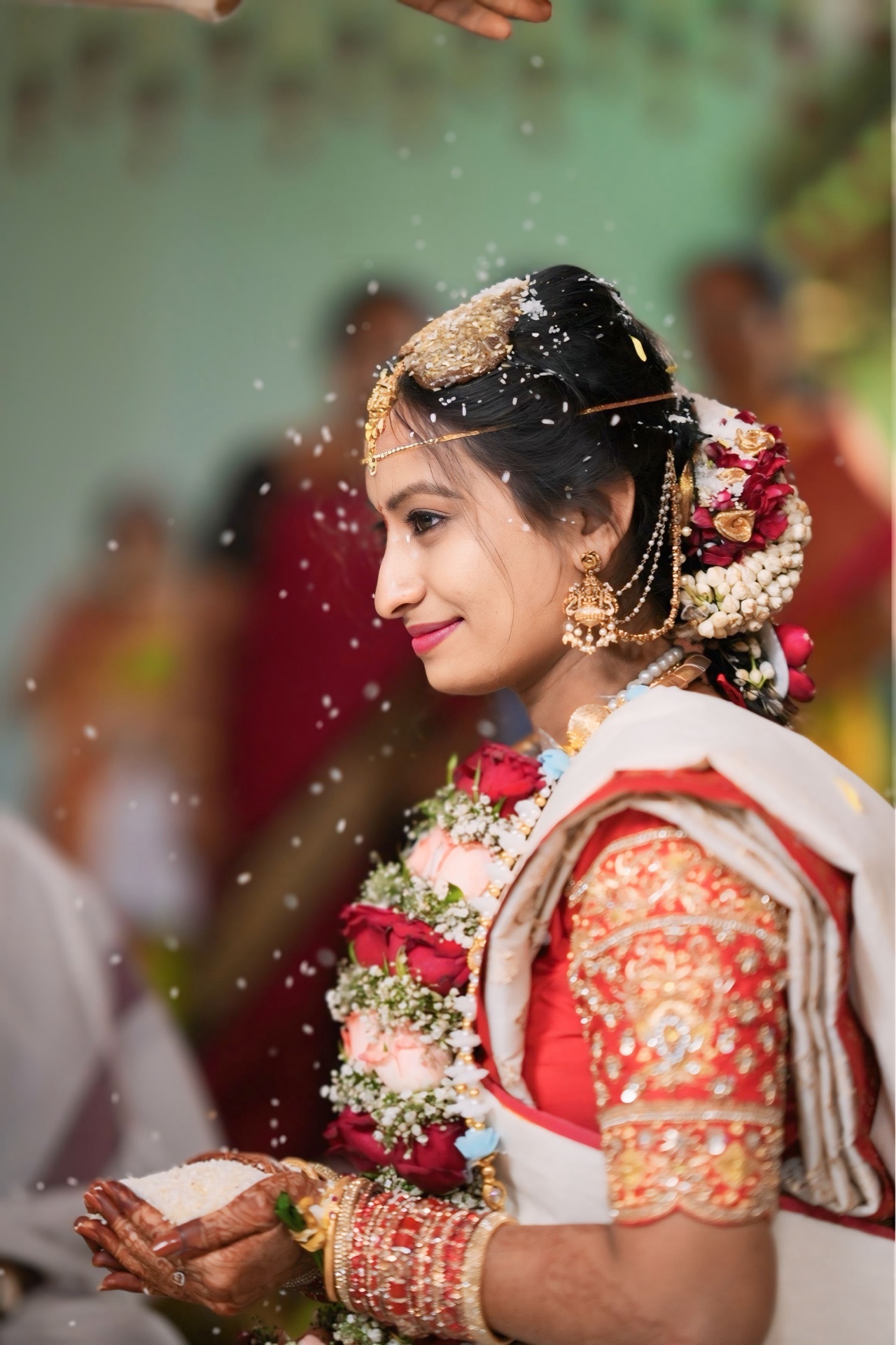 Bride smiling as blessings of rice fall around her