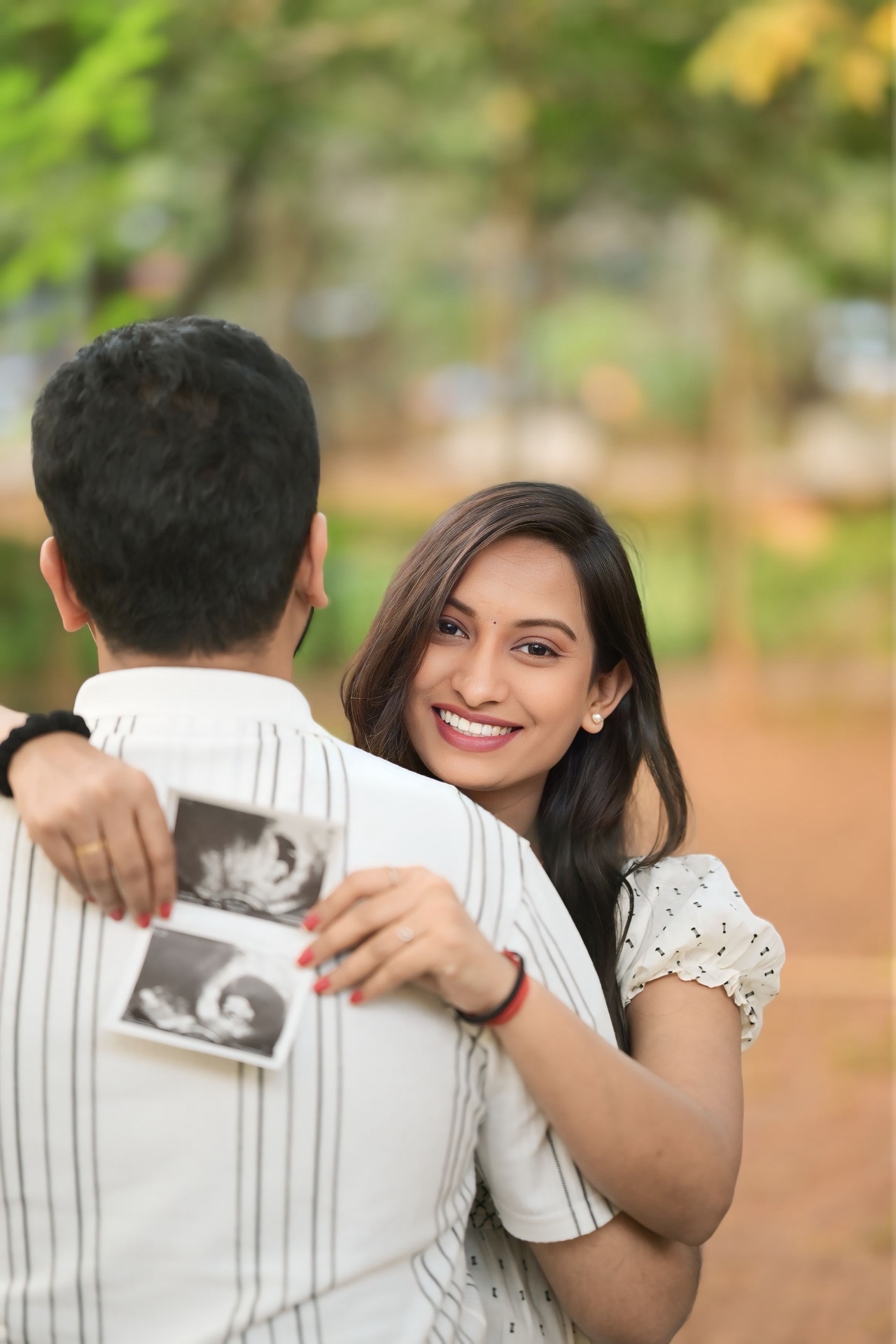 Expecting mother holding the ultrasound scan over her husband's shoulder